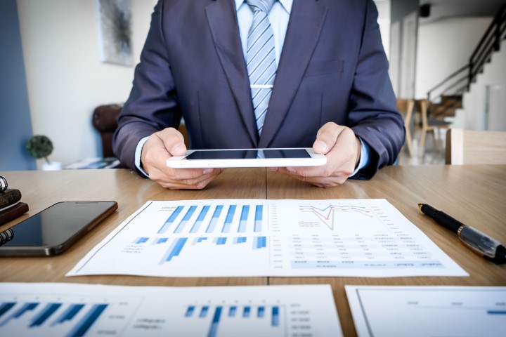 man-working-with-touchpad-while-sitting-couch-office-financial-statistic-graph